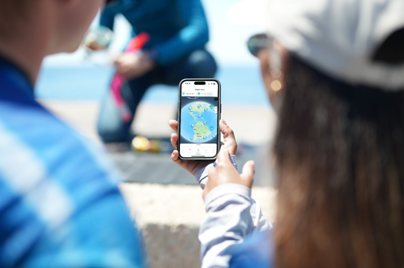Diver checking the Conservation Action Portal map on their phone at a beach cleanup